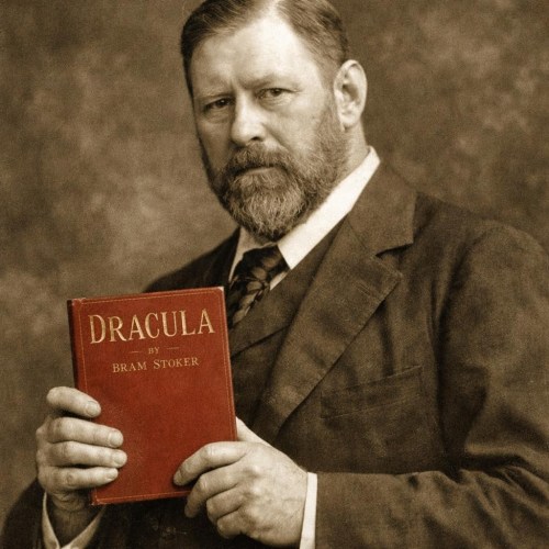 Man with beard holding a red book titled Dracula by Bram Stoker