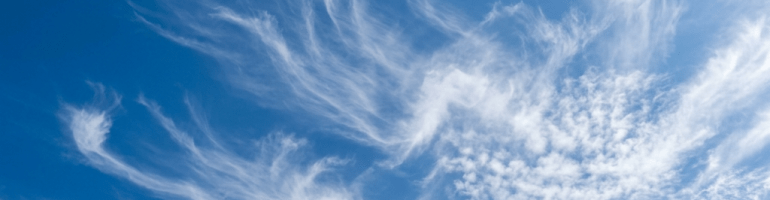 Feathery cirrus clouds scattered across a vivid blue sky