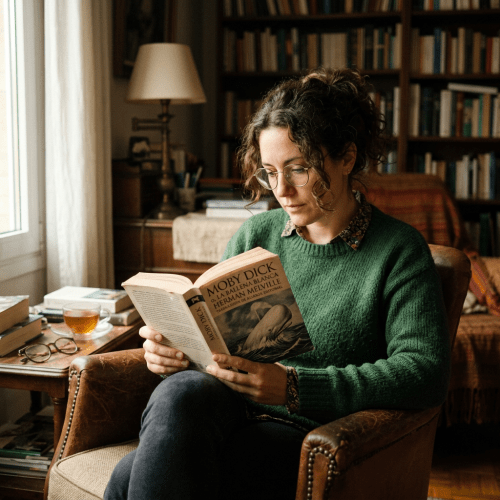 Woman in green sweater reading Moby Dick book indoors