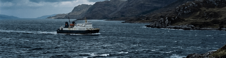 Ferry sailing past rugged mountains on a stormy coastal sea