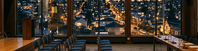 Empty conference room with chairs facing a city neighborhood at dusk